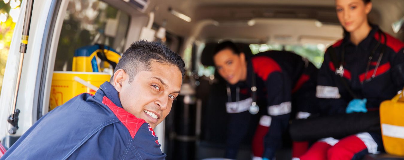 Three EMTs pose for a photo in an ambulance