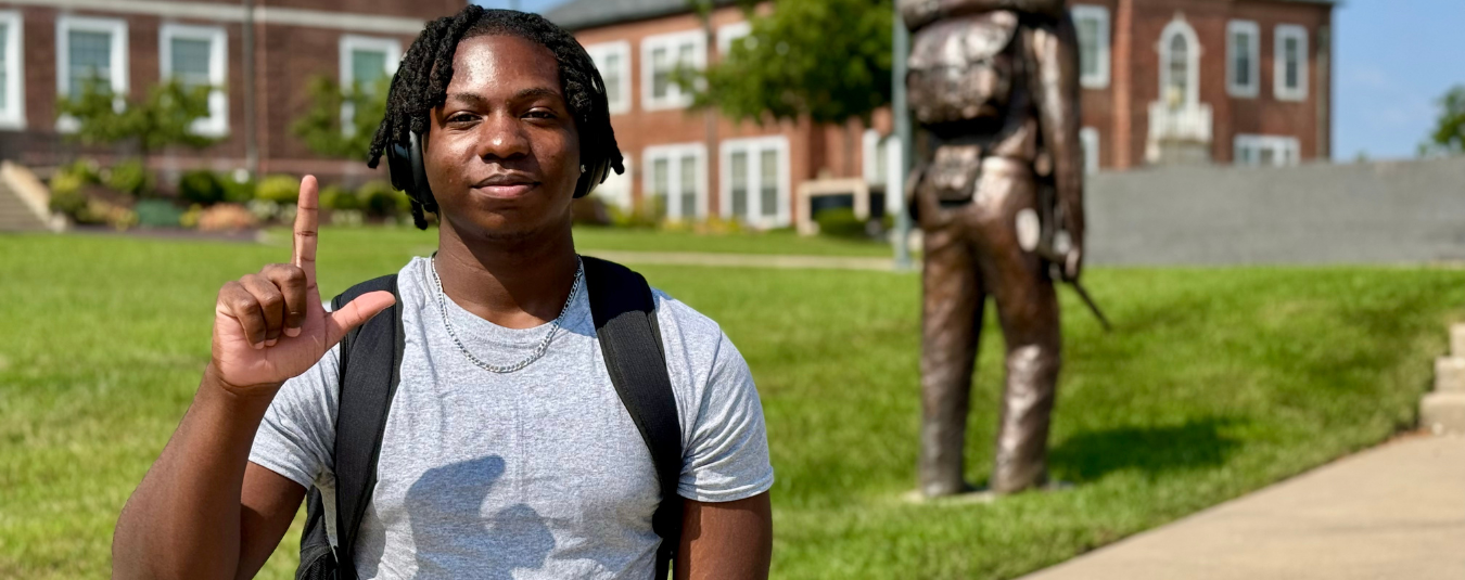 College student poses with 'number one' hand gesture on sunny campus at Lincoln University, Missouri