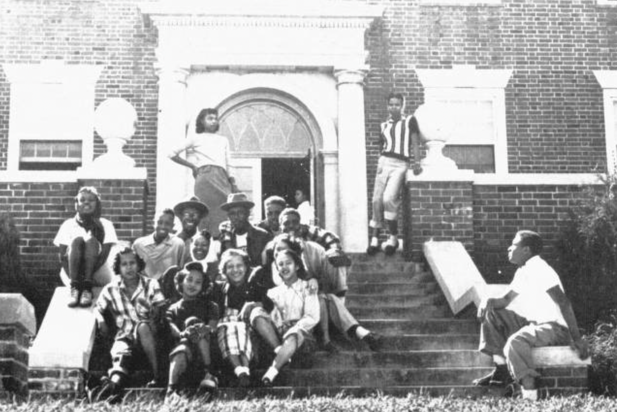 Freshman students at Lincoln University of Missouri sit on steps of a university building while smiling. 