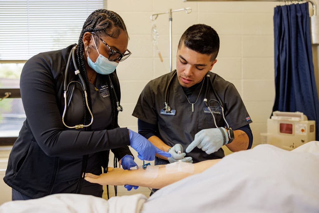 One female and one male nursing student work together to study a simulation maniken