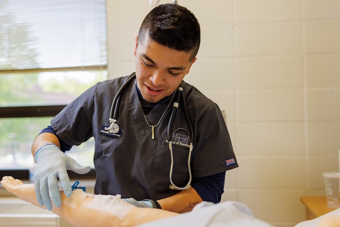 Male nursing student working in simulation lab.